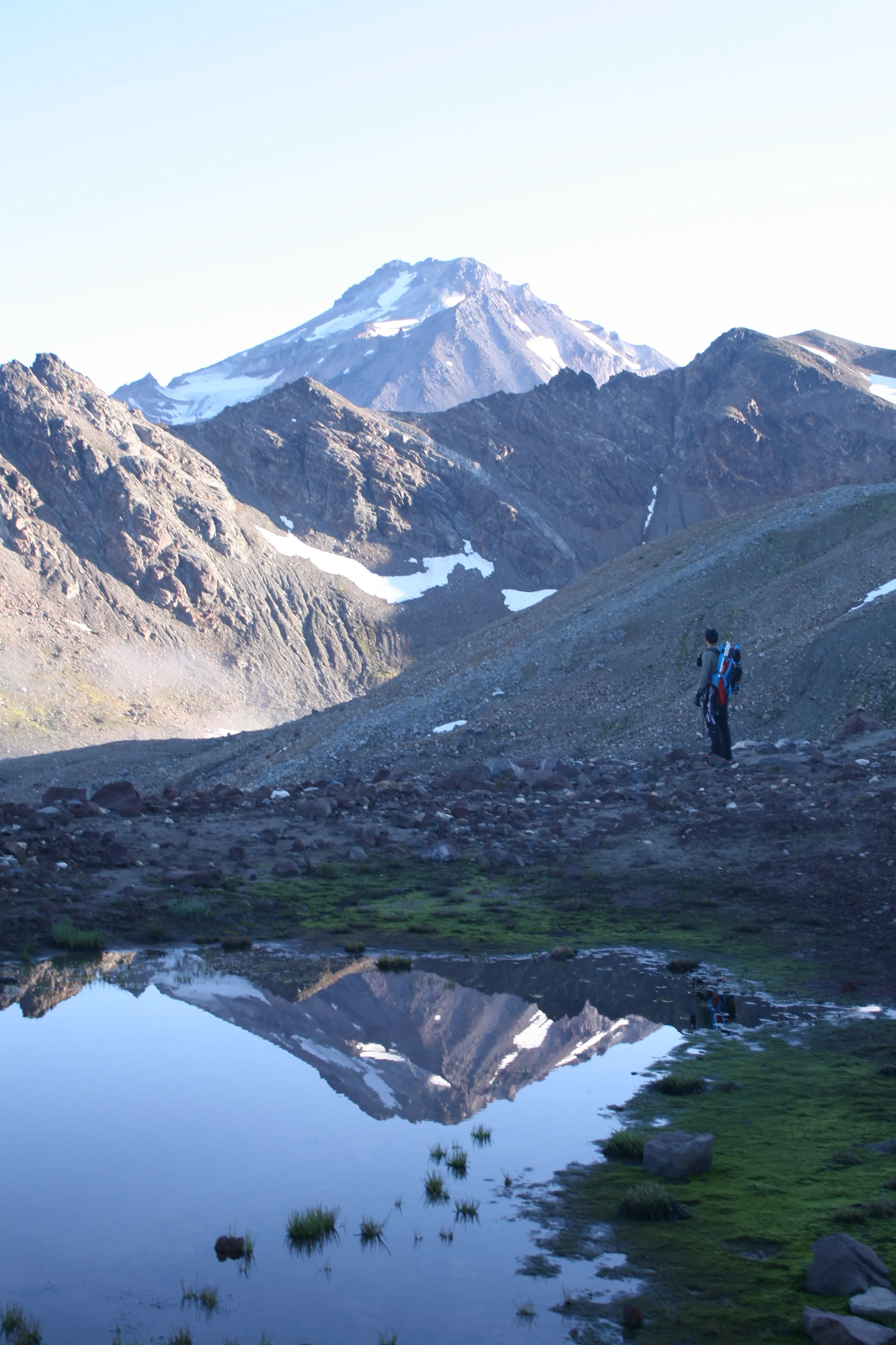 Jack by a tarn with Glacier Peak reflected in it