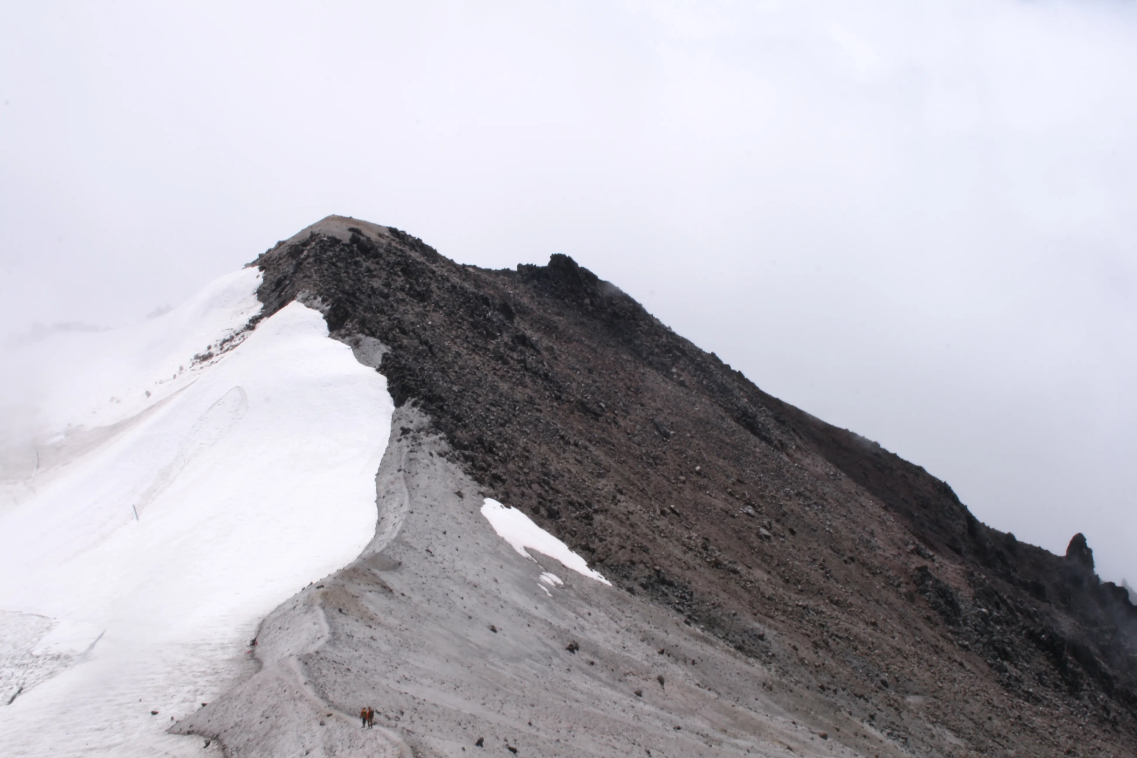 Two climbers making their final push for the summit across volcanic rock