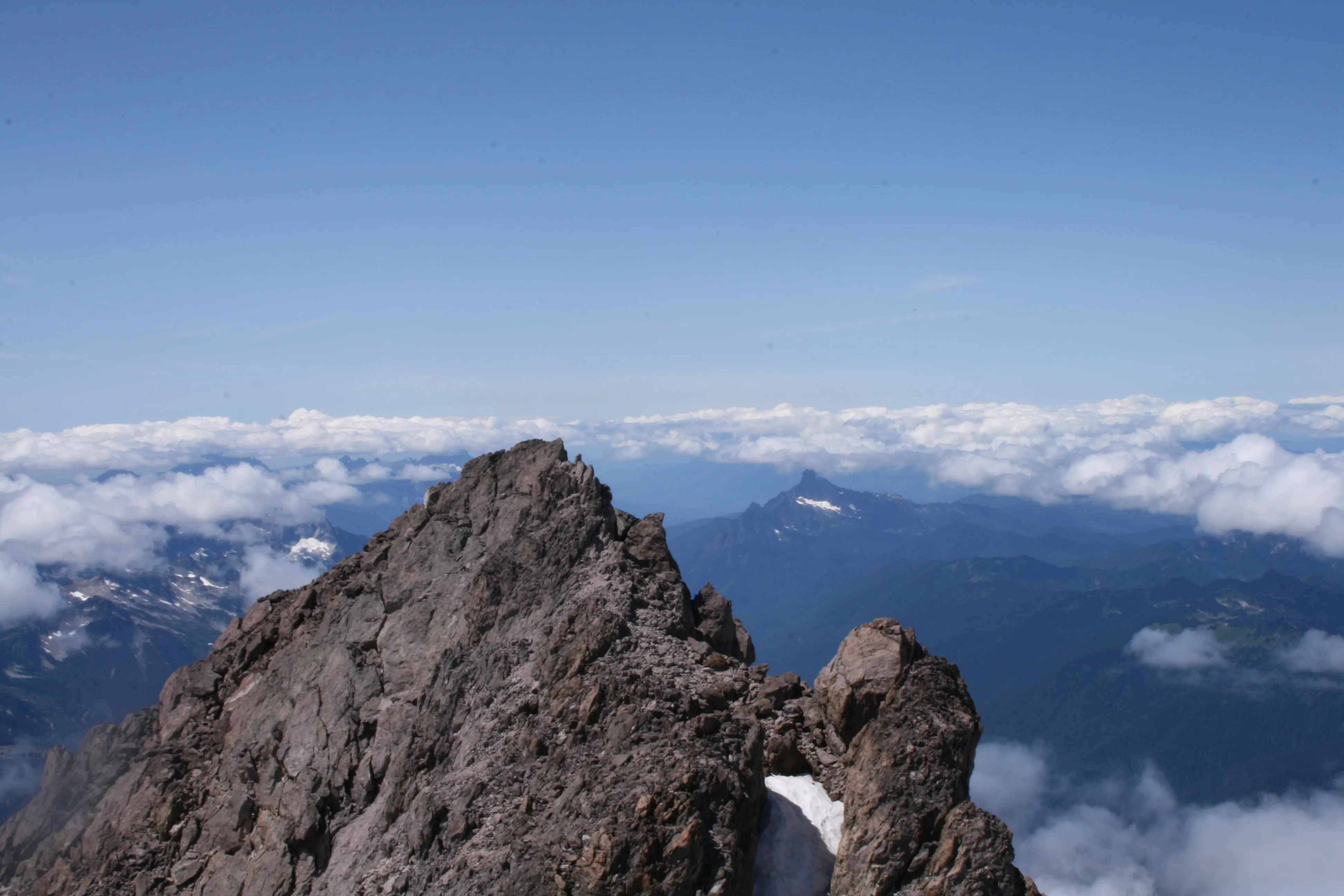 The view from the true summit block, with the sharp horn of Mount Pugh poking above the clouds to the west