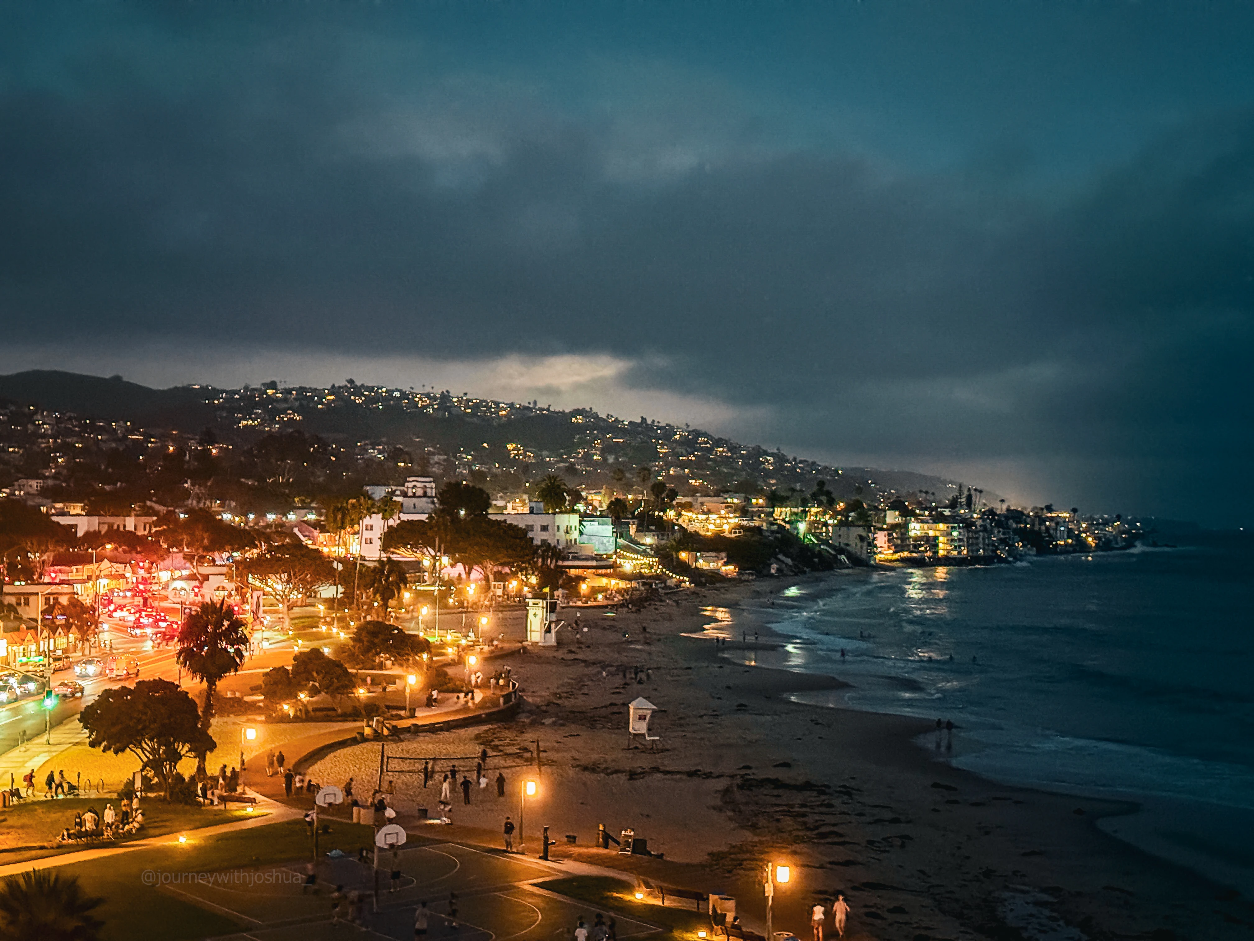 Marine layer rolling in at night over Laguna Beach, coast glowing underneath.