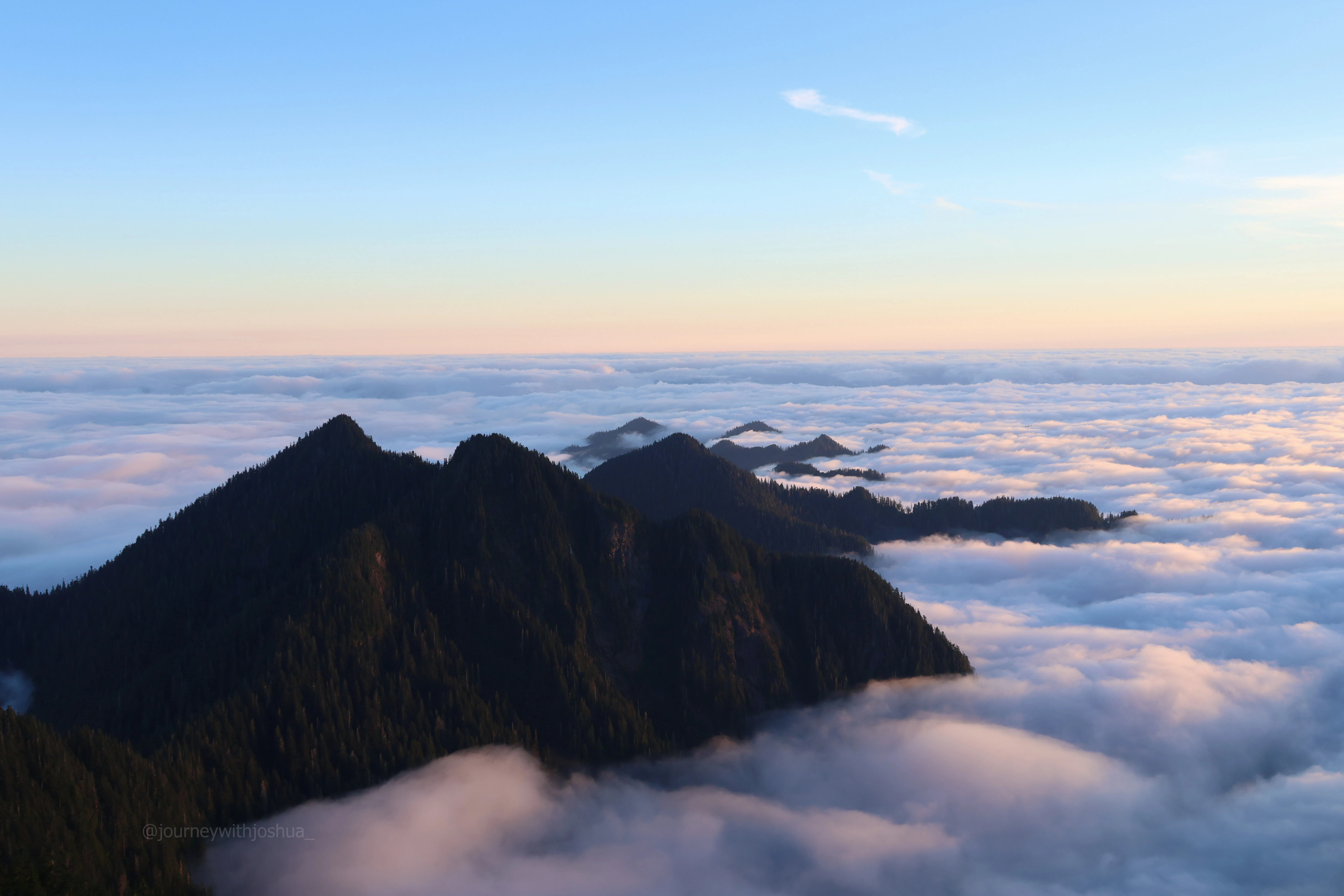 An endless sea of clouds at sunset engulfing the peaks of the Olympic Range.
