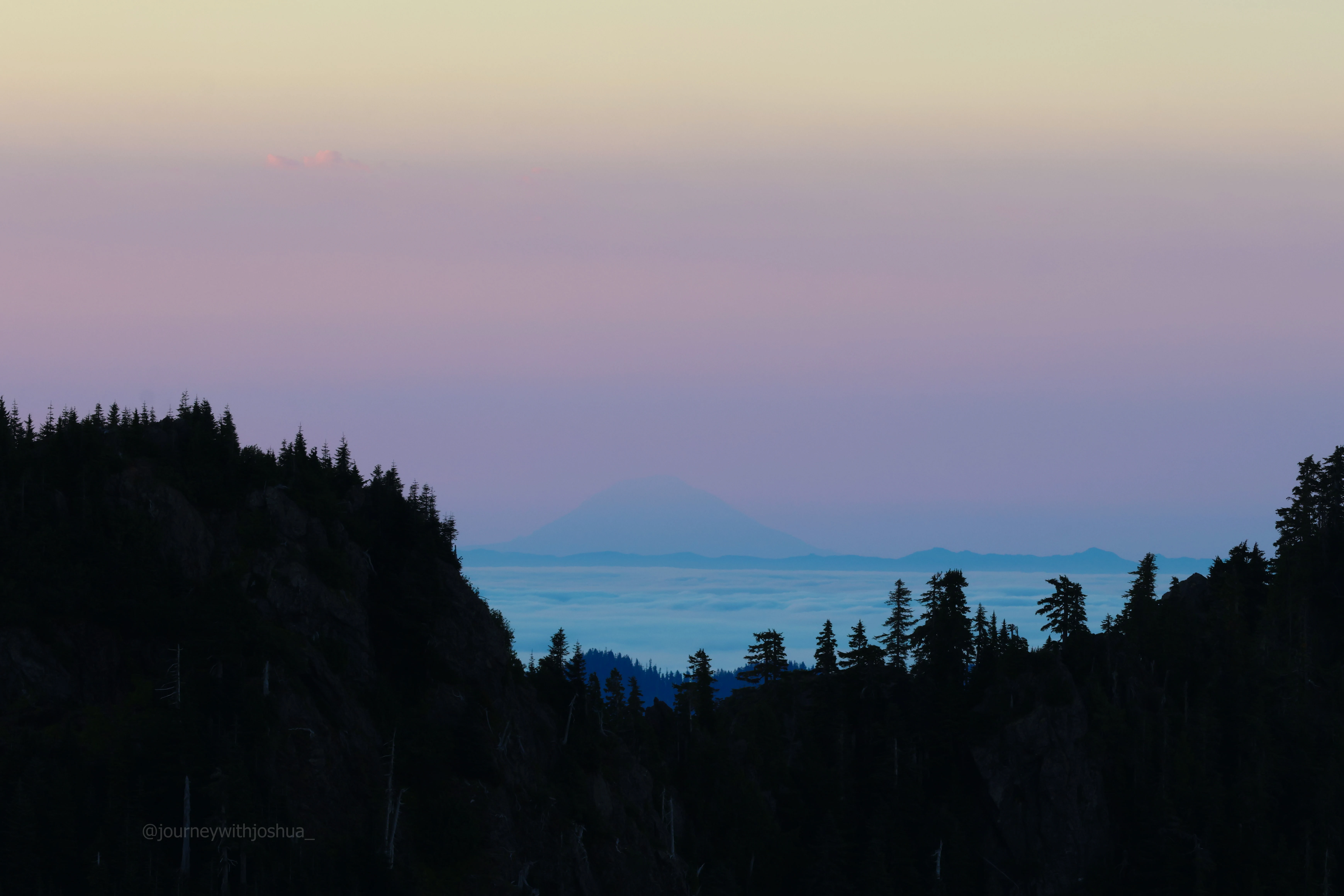 Hazy, moody Mount Adams in the fog as seen from the Olympic Range at sunrise.