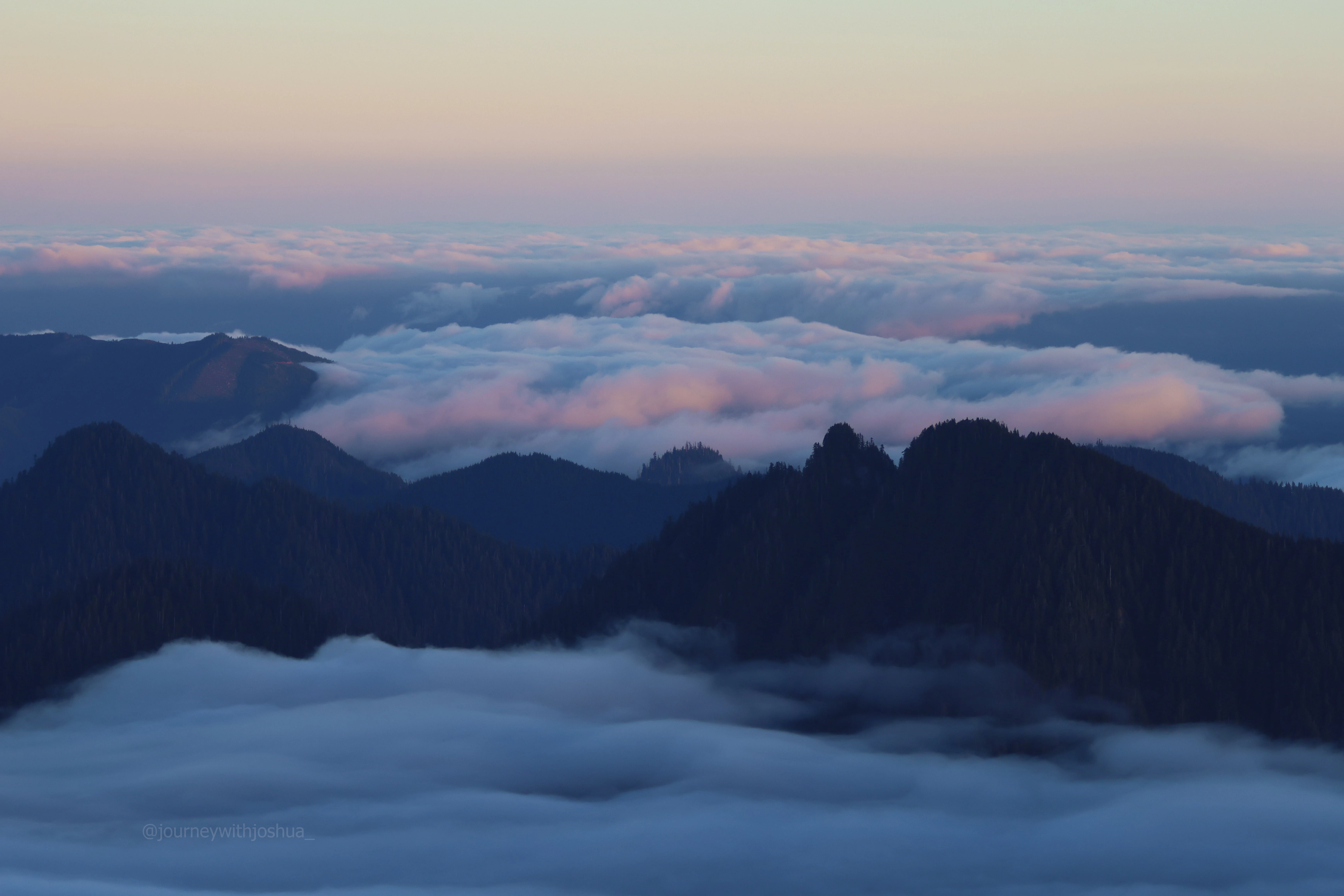 The cloud inversion flowing through the valley dips of the Olympic Range.