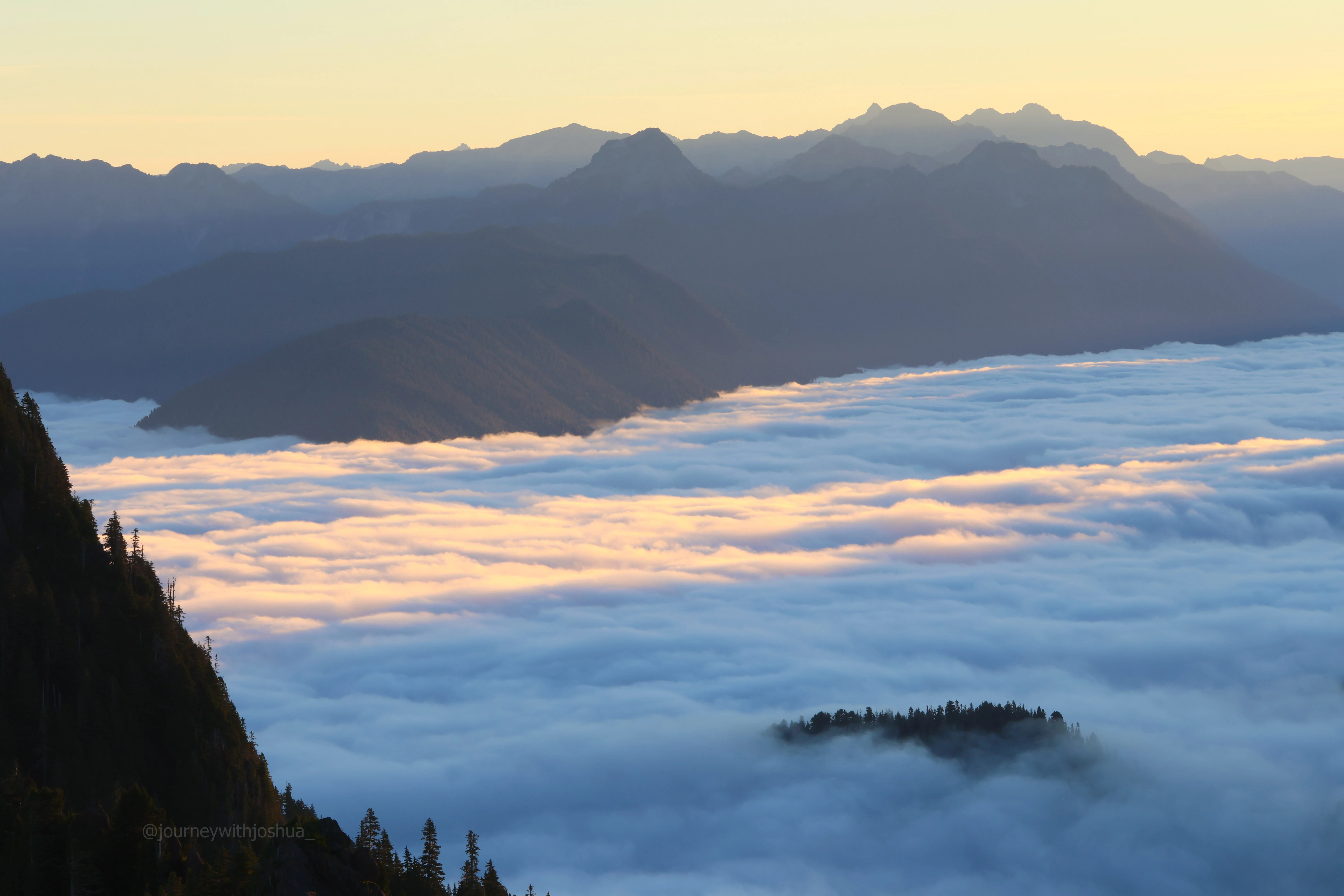 Mountain shadows sketched across the cloud inversion at sunrise in the Olympic Range.