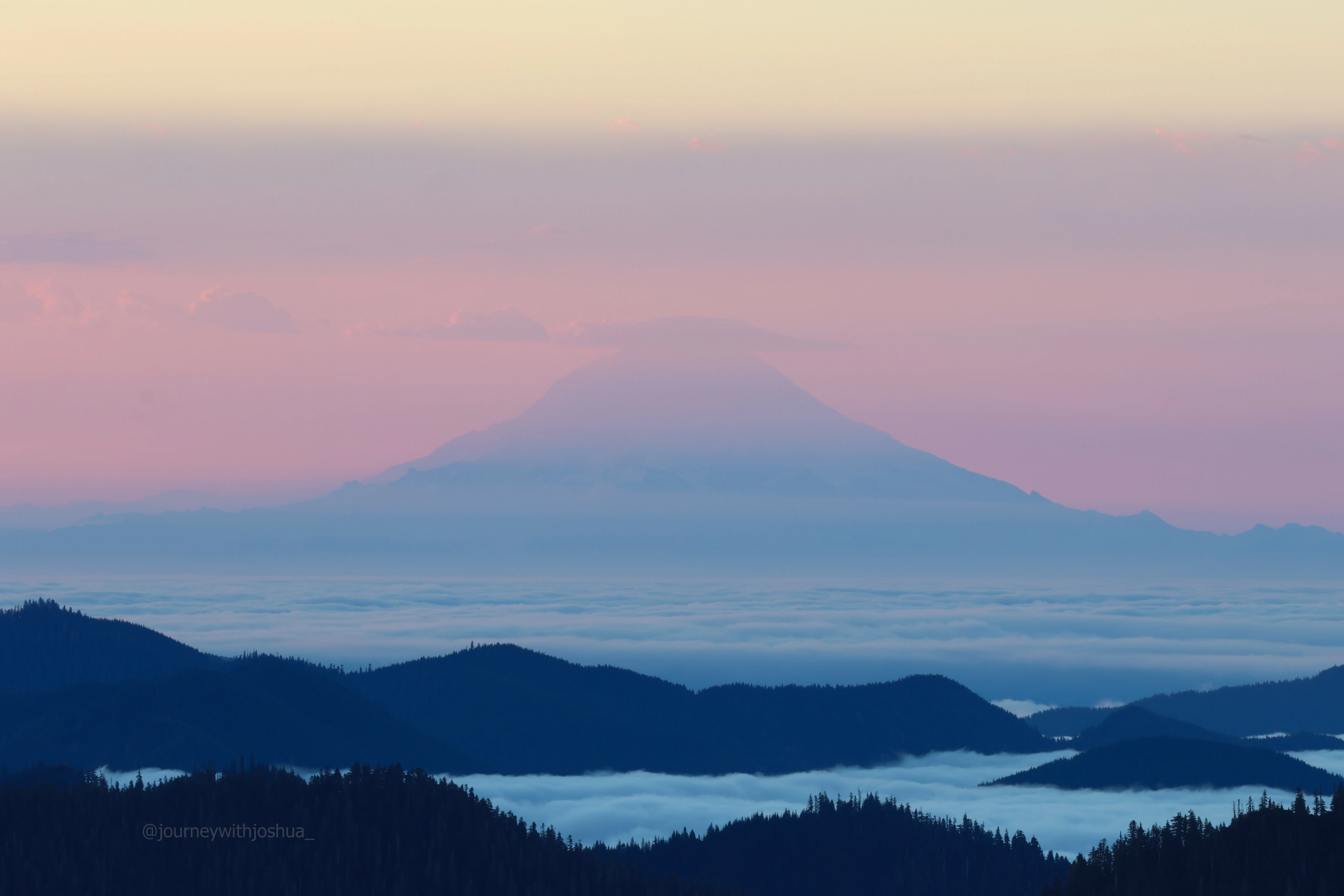 Mount Rainier standing tall in the moody morning haze as seen from the Olympic Range.