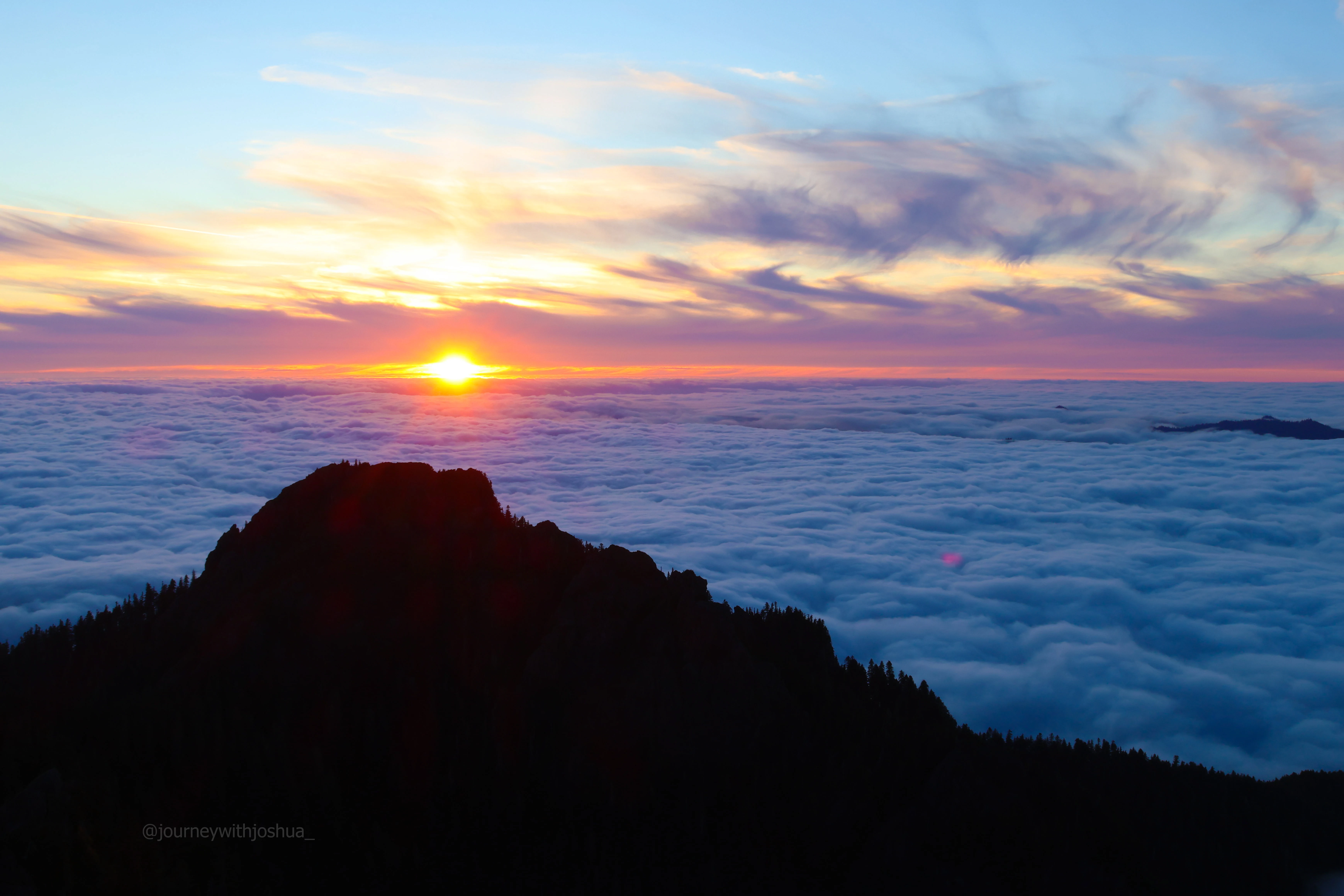 Sunset over the horizon and wispy clouds over the Olympic Range.