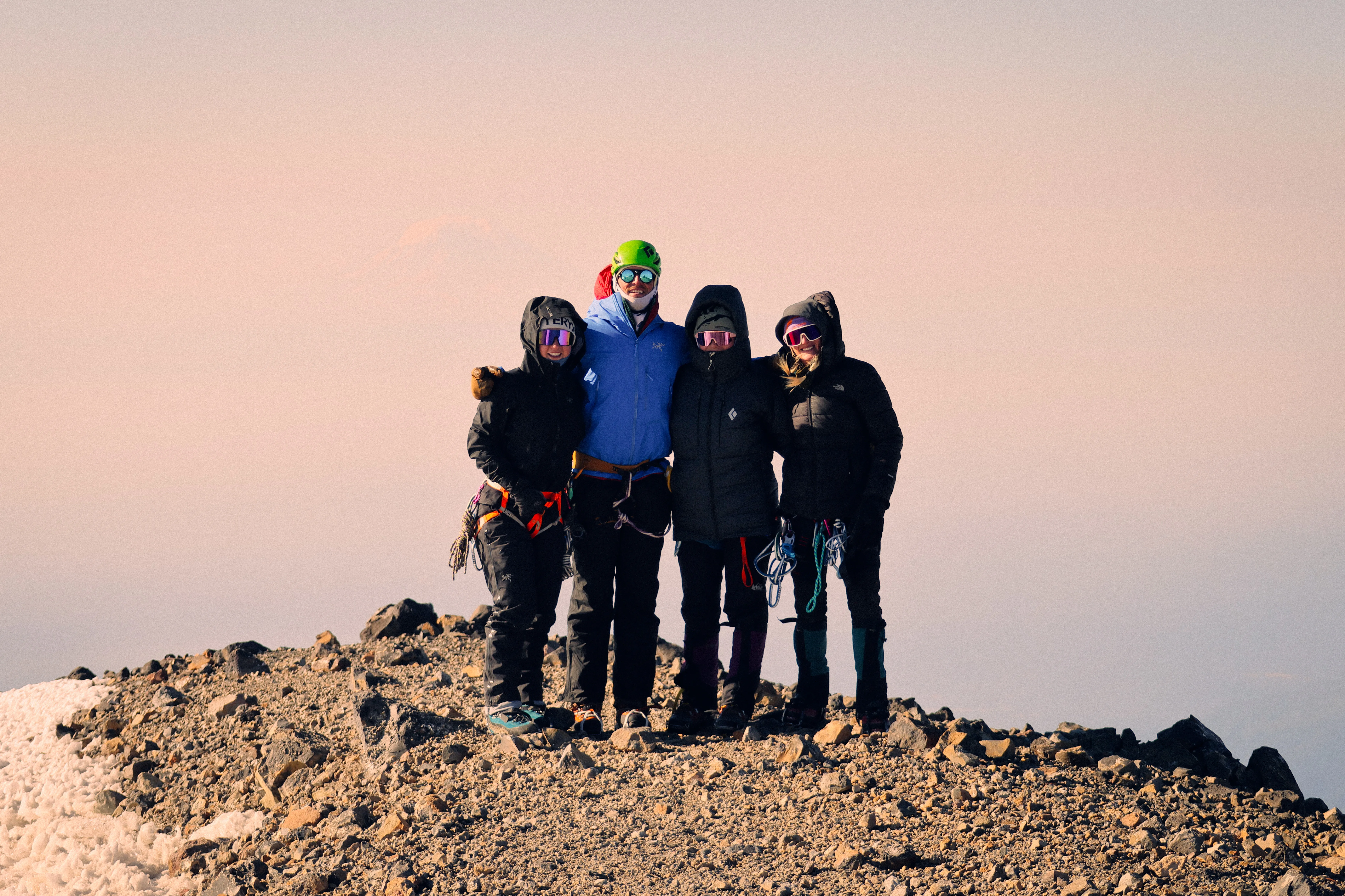 The team celebrating summit success with Mount Adams in a smoky background