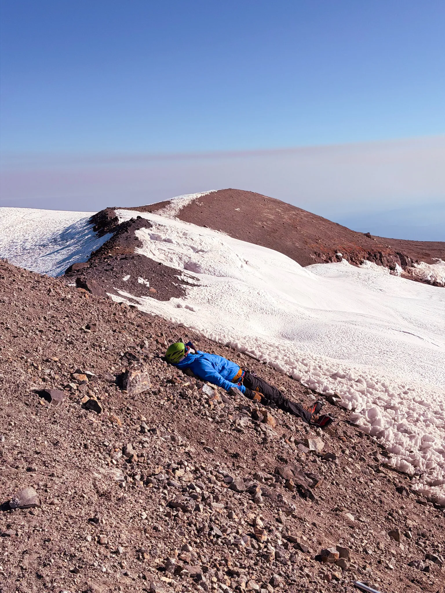 Lying down wasted at the summit, warming up hands and feet