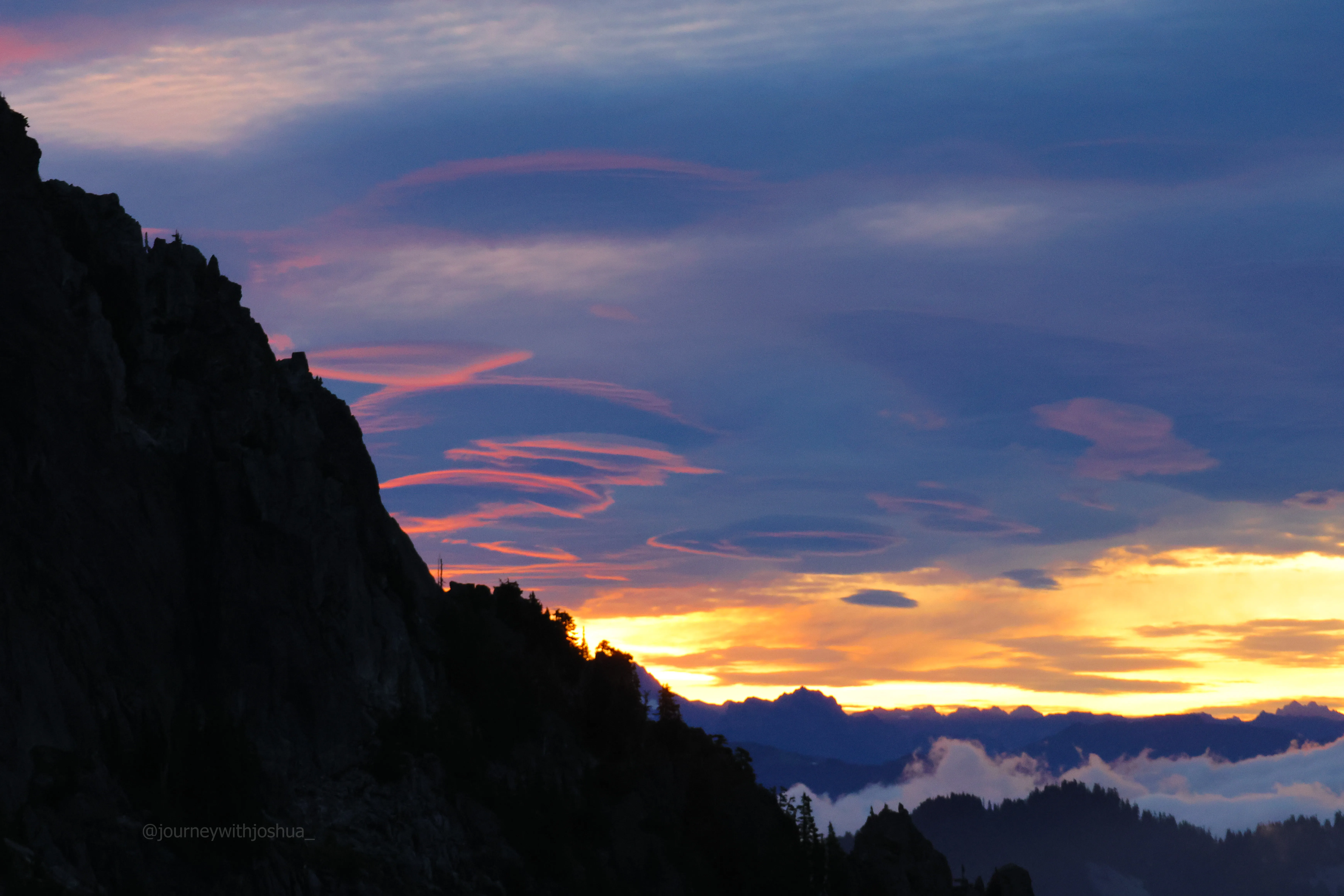 A cluster of lenticular clouds glowing pink like red blood cells in the sky