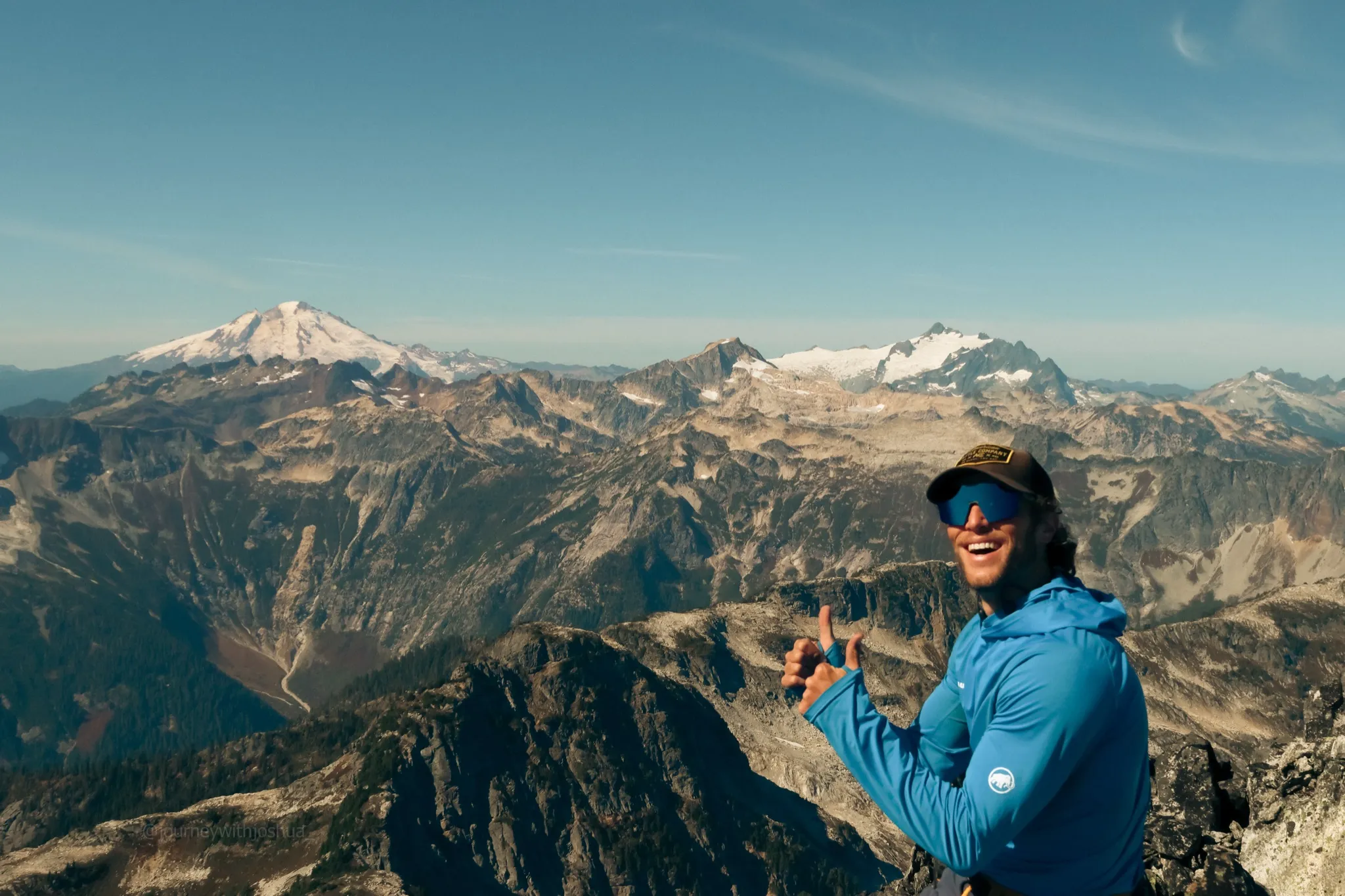 Mid-snack thumbs up on the summit of Mount Triumph with Mount Blum behind